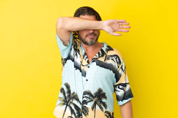 Senior dutch man isolated on yellow background covering eyes by hands - Photo, Image