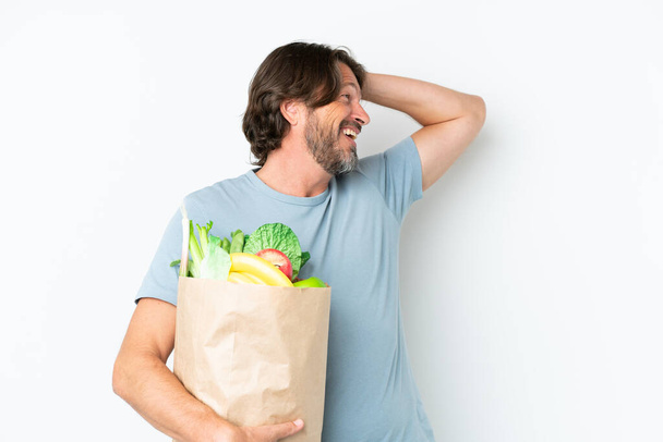 Starszy holenderski mężczyzna trzyma torbę na zakupy spożywcze na odosobnionym tle uśmiechając się dużo - Zdjęcie, obraz