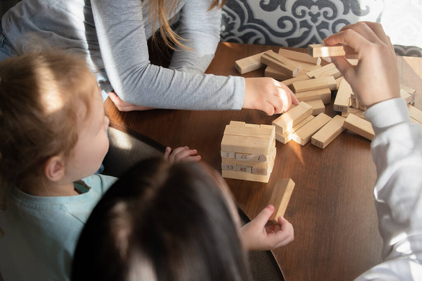 Children playing a board game with wooden sticks at home - Fotó, kép