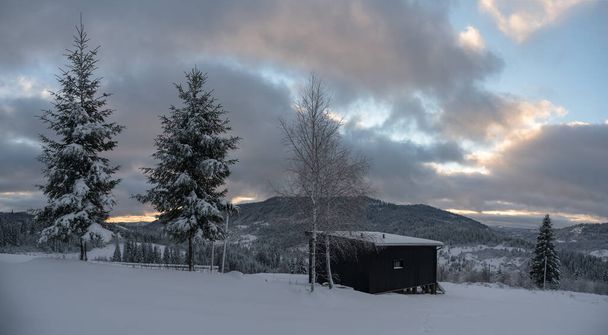 Panorama der schwarzen modernen winzigen Hütte auf schneebedeckten Karpaten in der Ukraine - Foto, Bild