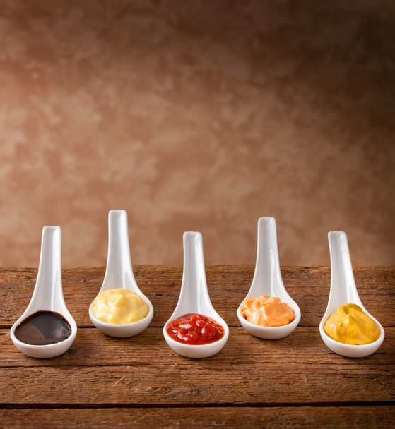 Salsas mezcladas en las cucharas de cerámica
 - Foto, imagen