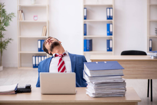 Giovane dipendente maschio e troppo lavoro in ufficio - Foto, immagini