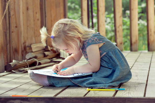 Little girl drawing with colored pencils on a country house wood - Photo, Image