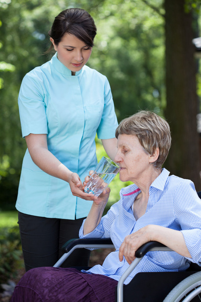 opiekun daje szklankę wody do starszych kobiety - Zdjęcie, obraz