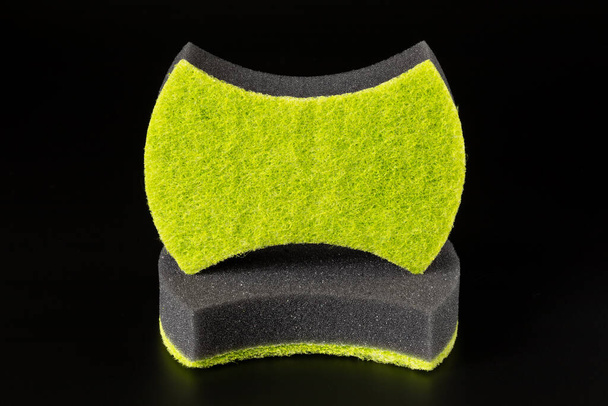 Две черные губки с абразивным ярко-зеленым слоем для мытья посуды и других бытовых или бытовых нужд изолированы на черном фоне. - Фото, изображение