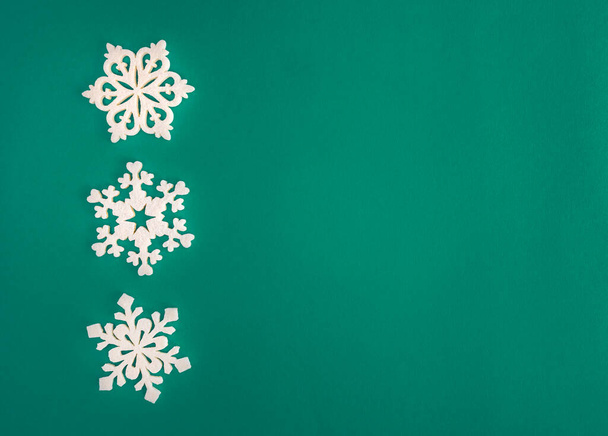 クリスマス休暇の組成、テキストのコピースペースと緑とアクアマリンの背景に白い雪の結晶の装飾を表示します。平置きだ。冬、ポストカードテンプレート. - 写真・画像