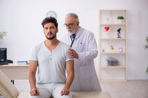 Young male patient visiting old male doctor - Foto, afbeelding