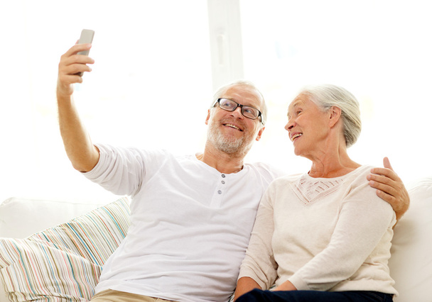 happy senior couple with smartphone at home - Fotó, kép