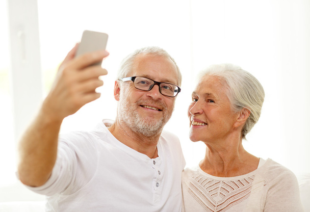 happy senior couple with smartphone at home - Фото, изображение