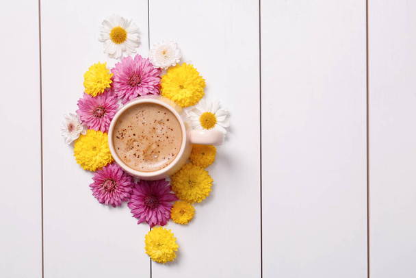 Beautiful floral composition with cup of hot coffee on white wooden background, flat lay. Space for text - Foto, Bild