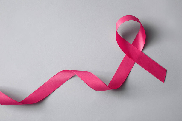 Pink ribbon on light grey background, top view. Breast cancer awareness concept - Zdjęcie, obraz
