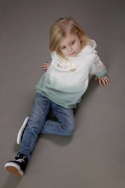 Studio portrait of toddler girl in jeans and hoodie - Фото, изображение