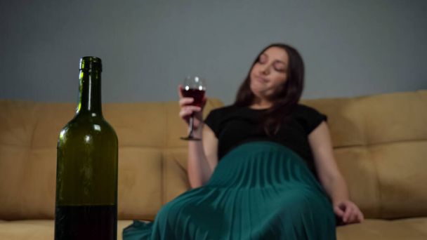 Wine bottle against blurry drunk woman sipping alcohol - Photo, Image
