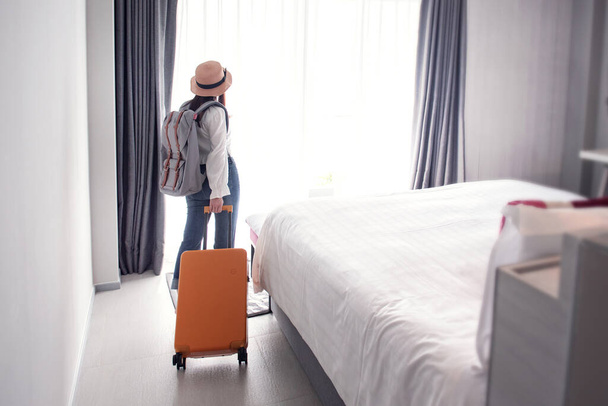 Kobieta turystyczna z bagażem w hotelu po zameldowaniu. Pojęcie podróży i wakacji. - Zdjęcie, obraz