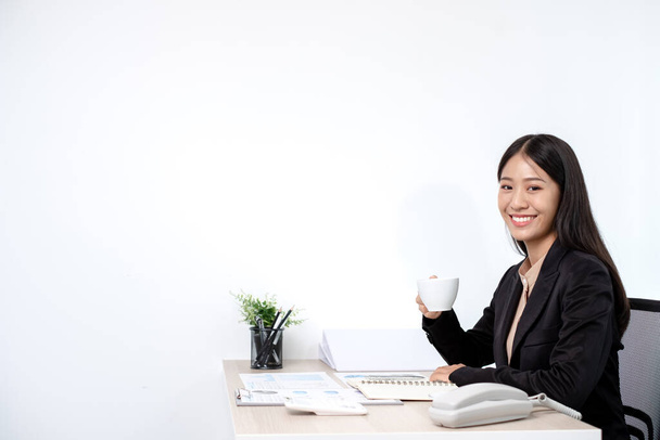 Asiatique femme d'affaires travaillant sur un ordinateur portable avec un sourire joyeux et heureux tout en travaillant à boire du café le bureau. - Photo, image