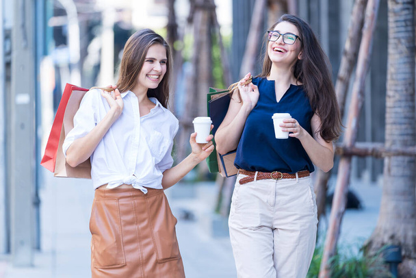 Schöne Frau mit Einkaufstaschen und heißem Kaffee. Schöne Frau genießt mit Papiereinkaufstasche und heißem Kaffee zu Fuß vor dem Geschäft. - Foto, Bild
