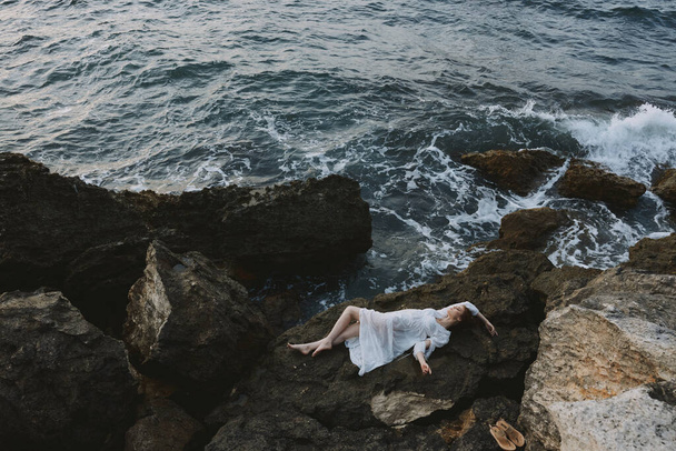 beautiful woman in a white dress lying on a stone in a white dress view from above - Foto, imagen