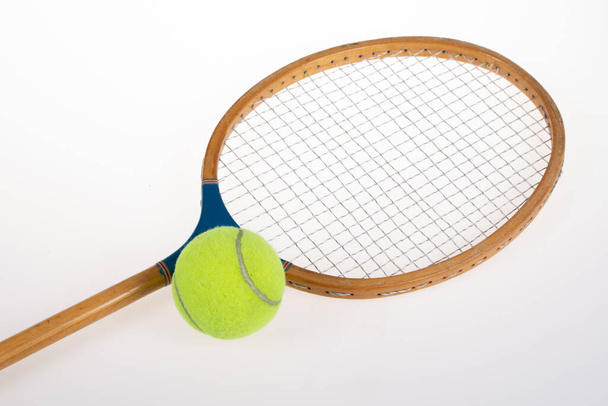 Εσοδεία ρακέτα τένις με κίτρινη μπάλα σε γκρι φόντο - Φωτογραφία, εικόνα