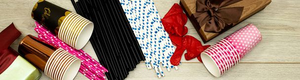 банер концепції свят: Різдво або день народження, одноразові чашки та соломинки та подарункові коробки на дерев'яному столі
 - Фото, зображення