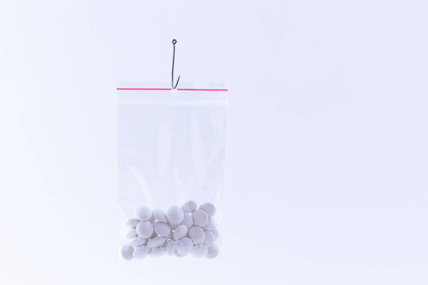 White Pills or Tablets Hanging in Small Ziplock Bag on a Fishing Hook - Photo, Image