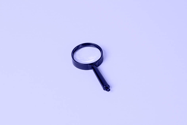 Zwart vergrootglas op lichtblauw Zeer Peri kleur achtergrond. - Foto, afbeelding