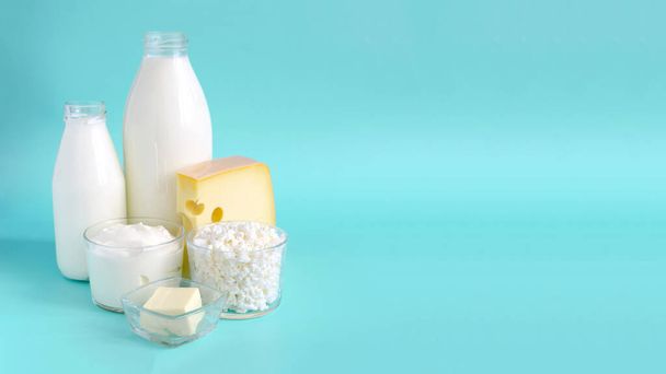 The concept of consumption of milk products. Milk, kefir, sour cream, cheese, butter and cottage cheese in a glass container on a light background of kopi space - Φωτογραφία, εικόνα
