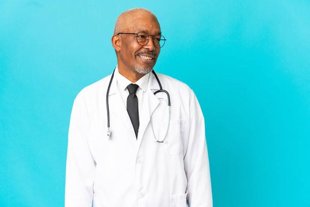 Senior arts man geïsoleerd op blauwe achtergrond uitziende kant - Foto, afbeelding