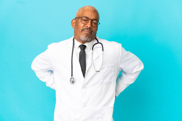 Senior arts man geïsoleerd op blauwe achtergrond die lijden aan rugpijn voor het hebben van een inspanning - Foto, afbeelding