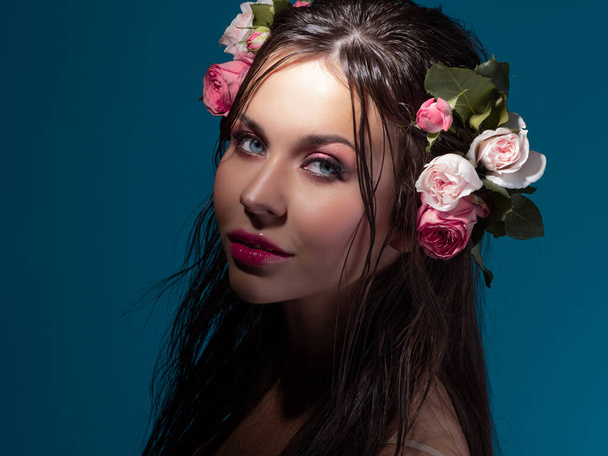 A young beautiful woman with rose flowers in her wet hair. - Photo, Image