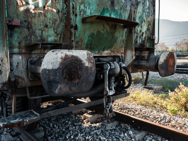 Achterzijde van een goederenwagon met buffers en haken die wachten op aansluiting op de rest van de spoorvoertuigen om een goederentrein bovenop het spoor samen te stellen - Foto, afbeelding