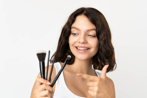 Teenager ukrainische Mädchen isoliert auf weißem Hintergrund hält Make-up-Pinsel und zeigt es - Foto, Bild