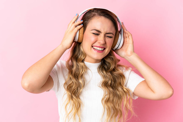 Nuori brasilialainen nainen eristetty vaaleanpunainen tausta kuuntelee musiikkia - Valokuva, kuva