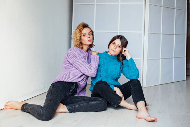 twee vriendinnen naast elkaar in warme kleren thuis - Foto, afbeelding