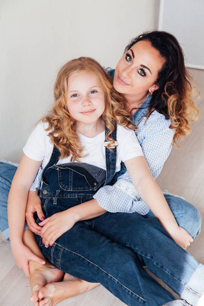 Mutter und Tochter in Jeans umarmen und lächeln - Foto, Bild