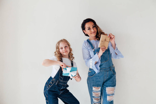 Mutter und Tochter in Jeans halten Geschenke für den Urlaub in den Händen - Foto, Bild