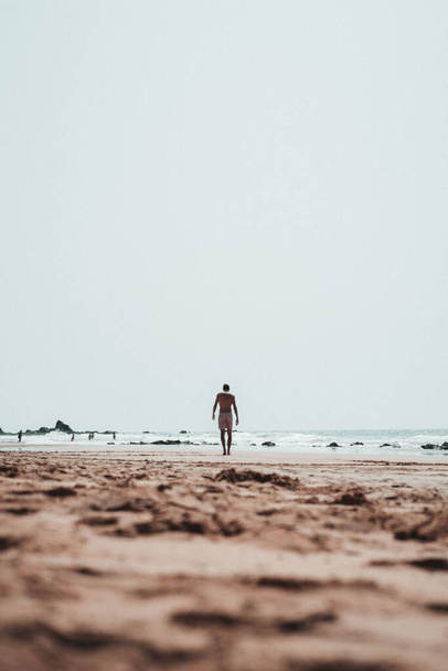 A vertical shot of a boy walking on a beach - Zdjęcie, obraz