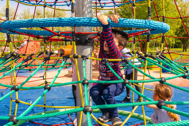 POZNAN, POLAND - May 18, 2019: A young boy climbing on a rope net in a playground at the Rataje park - Foto, immagini
