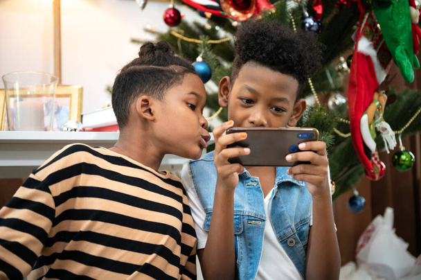 Happy afro hair kid boy play smart phone with Christmas decorations - Фото, зображення