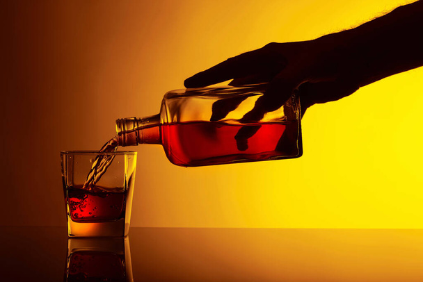 Versare la bevanda alcolica da una bottiglia in un bicchiere. Copia spazio. - Foto, immagini