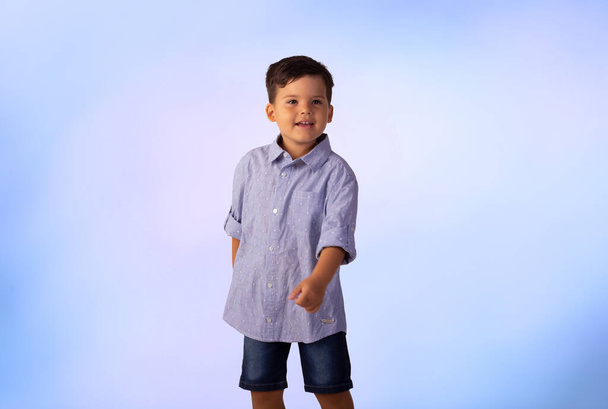 male child in studio photo with blue background wearing shirt and jeans. - 写真・画像