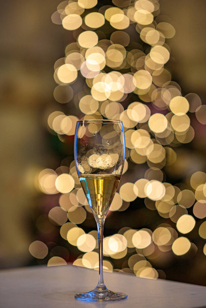Closeup wine glass at new year tree background. New year bokeh light texture - Zdjęcie, obraz