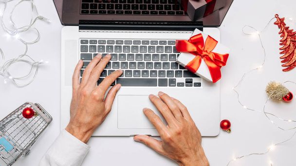 Christmas online store. Gift box red ribbon, trolley and laptop, money in flat lay internet online shopping composition. Xmas shop, top view. - Fotoğraf, Görsel