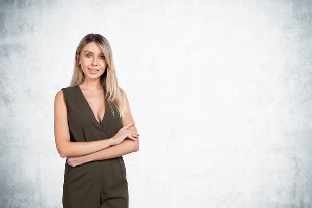 Office blonde woman in jumpsuit, smiling and looking at the camera. Copy space empty grey wall. Concept of startup and business plan - Foto, imagen