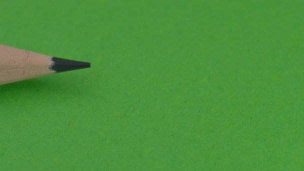 Prosty drewniany ołówek pojawia się po lewej stronie, jest zablokowany ołówkiem po prawej stronie z gumką na zielonym tle, klip wideo, zbliżenie - Materiał filmowy, wideo
