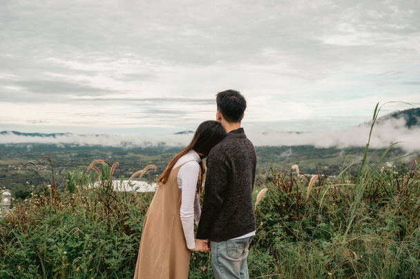 Zadní pohled asijského páru stojí objímání a držení se za ruce při pohledu na přírodu v přírodě na dovolené - Fotografie, Obrázek