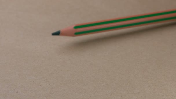 La lucha de dos lápices verdes termina con la victoria del pequeño sobre una superficie de cartón marrón, video clip, primer plano - Imágenes, Vídeo