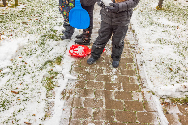 Näkymä naisen ja lasten jalat lumisella jalkakäytävällä. Perhe liukuu alamäkeen lumilaudoilla..  - Valokuva, kuva