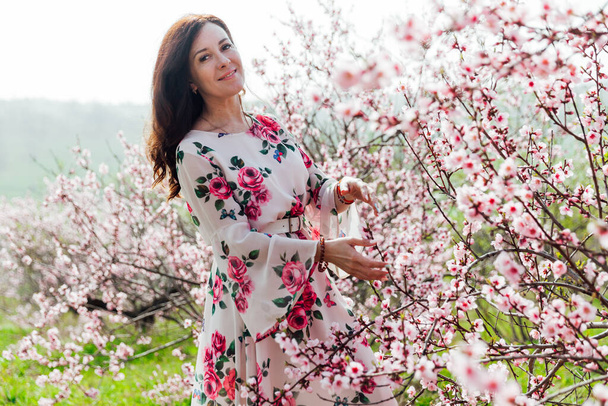 όμορφη γυναίκα σε ένα φόρεμα άνοιξη σε ένα ανθισμένο κήπο τριαντάφυλλο - Φωτογραφία, εικόνα