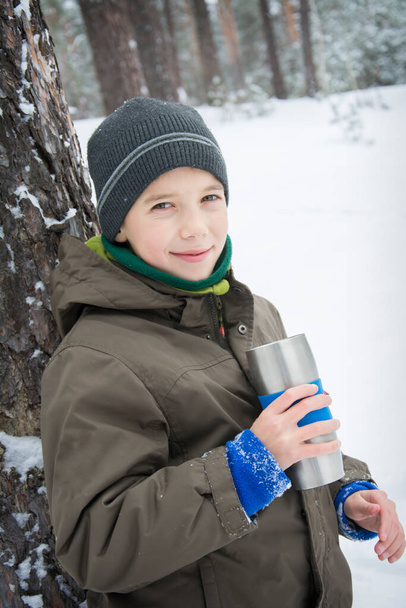 No inverno, um menino bebe chá em uma floresta nevada. - Foto, Imagem