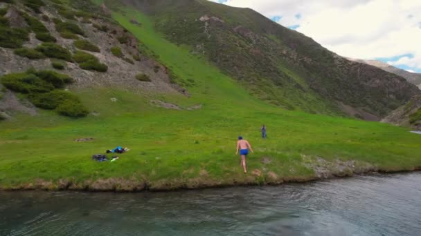 An athlete gets out of a pond in the mountains, shakes his hands - Filmmaterial, Video
